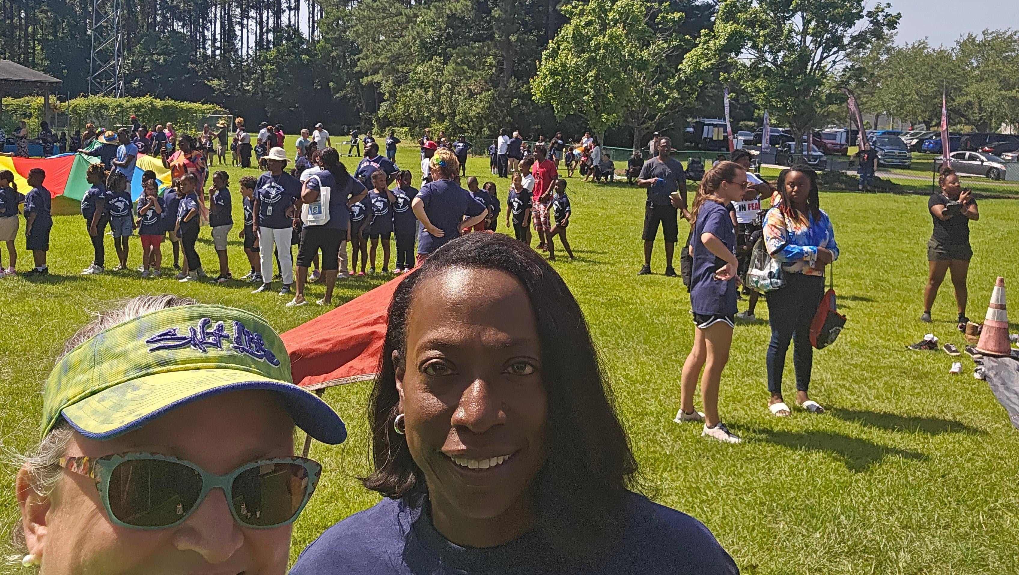 A selfie of two people at a community event at a park
