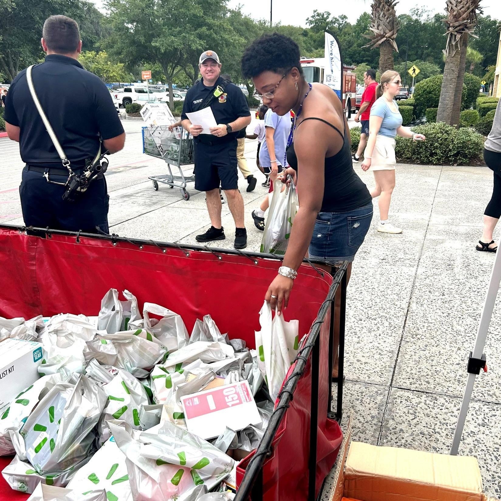 A person grabbing a bag from a bin of many bags with items in them.