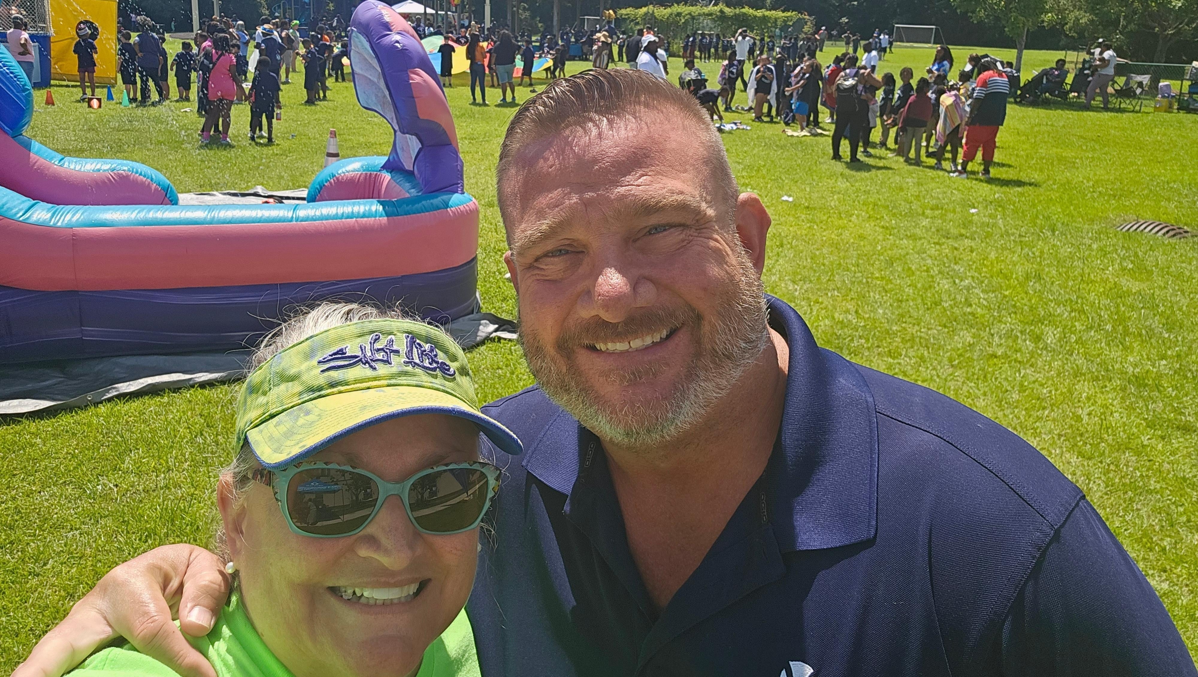 A selfie of two people at a community event at a park